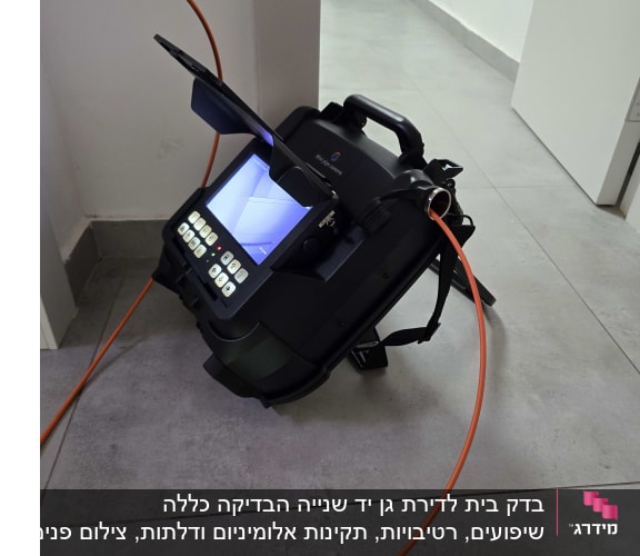 מכשיר בדיקה עם מסך וכבל כתום על רצפה